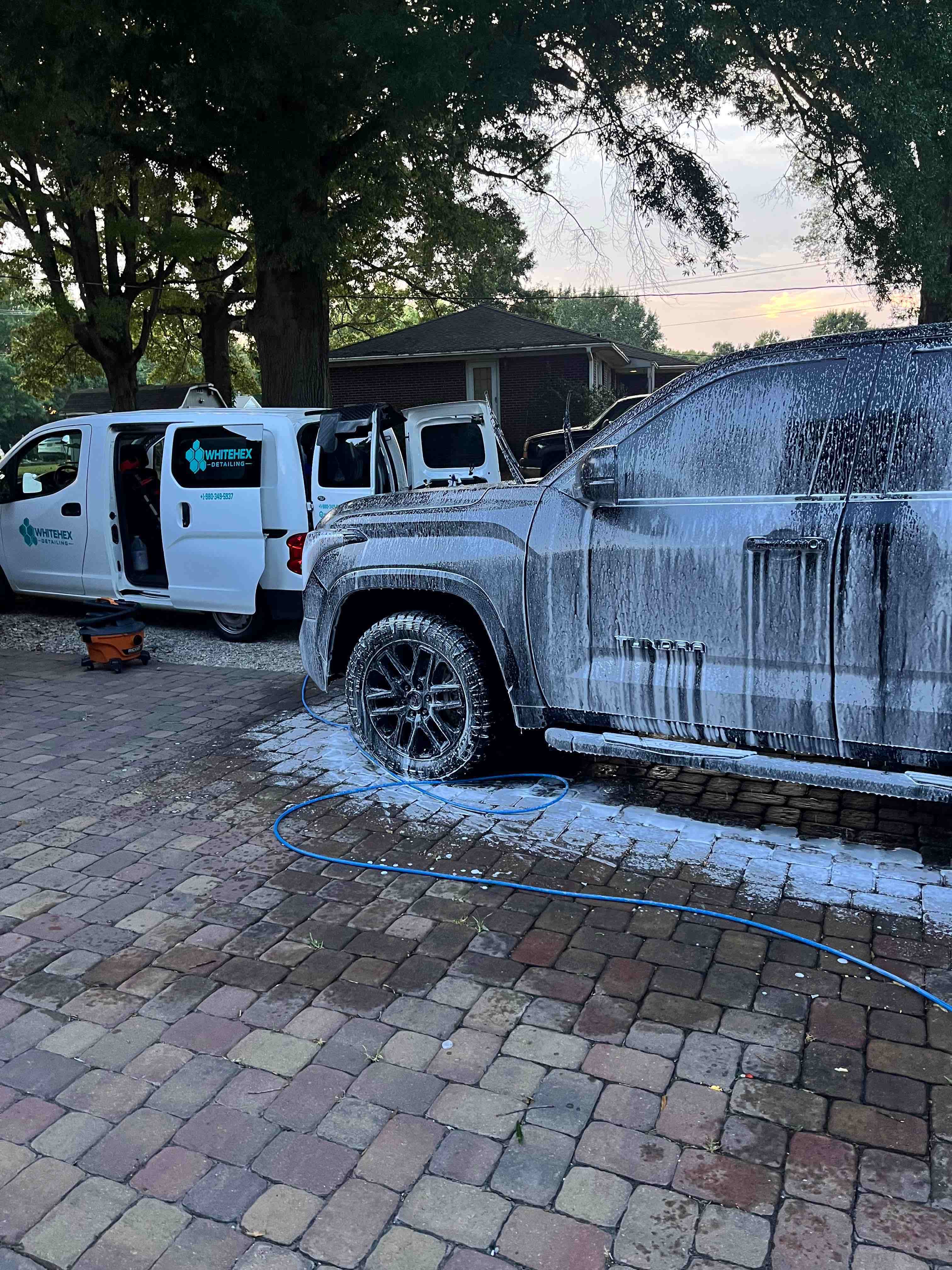 White detailing van beside a pickup truck during a wash